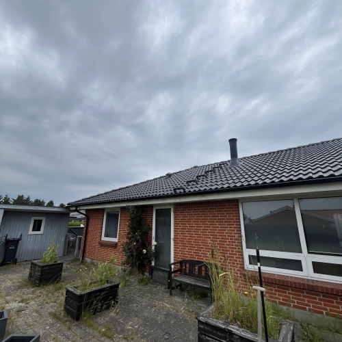 hus med nyt tag og overgroet indgang